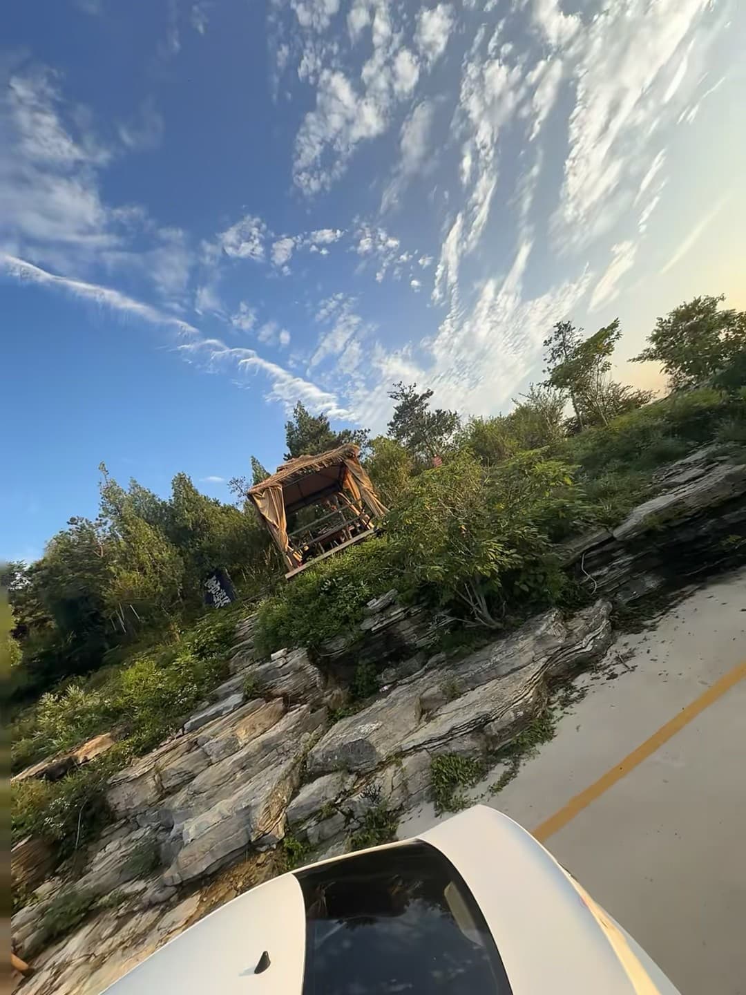 今天在山边小路停了下，车顶刚好框住这顶草棚——蓝天和乱石堆，像被风揉过的旧画封面图
