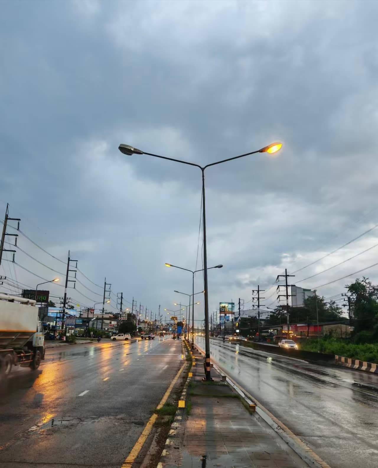 雨后路灯亮起，车灯在湿路上拉长成金线封面图