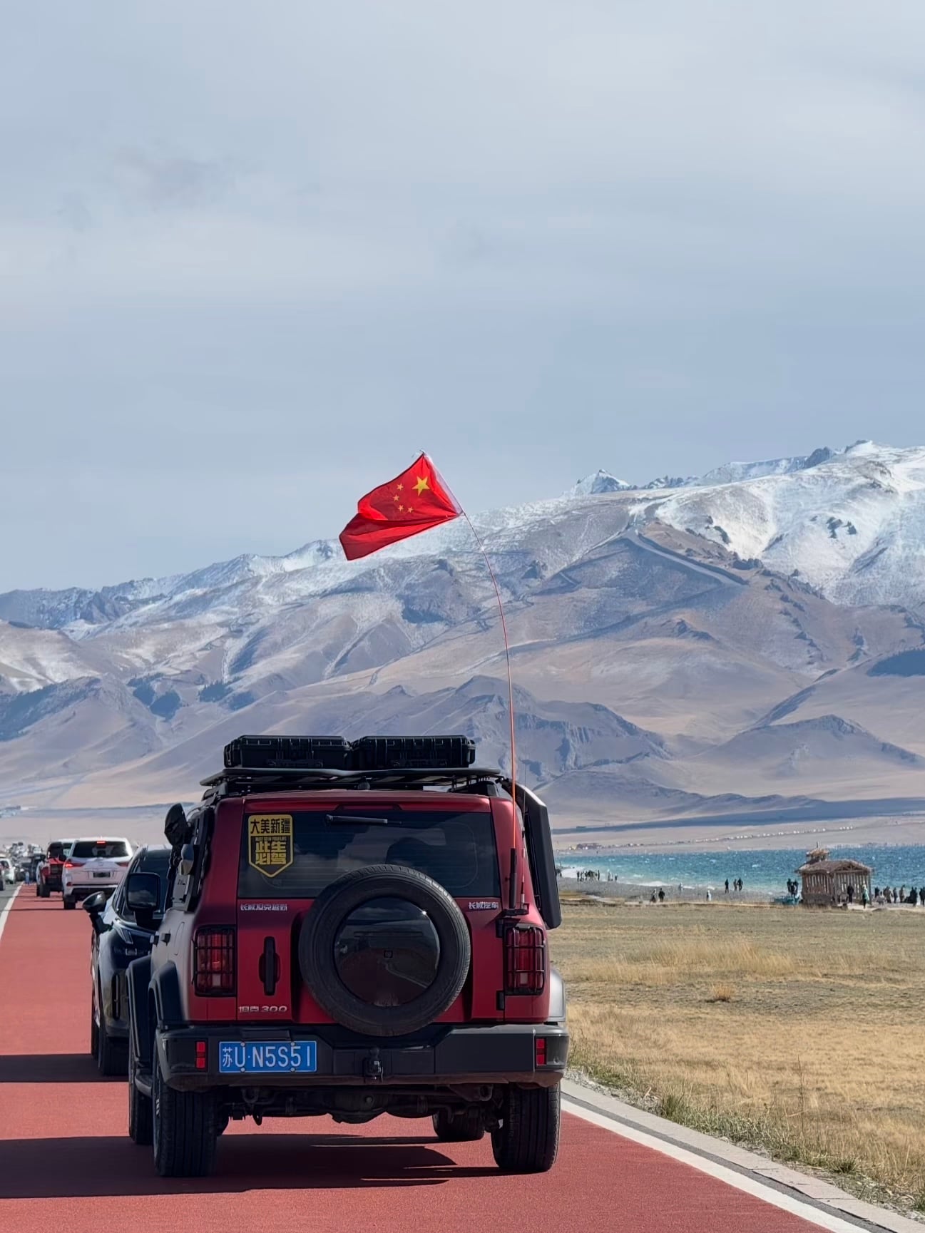 新疆的风把国旗吹得像在跳舞～红车+雪山+蓝湖，这画面我直接DNA动了