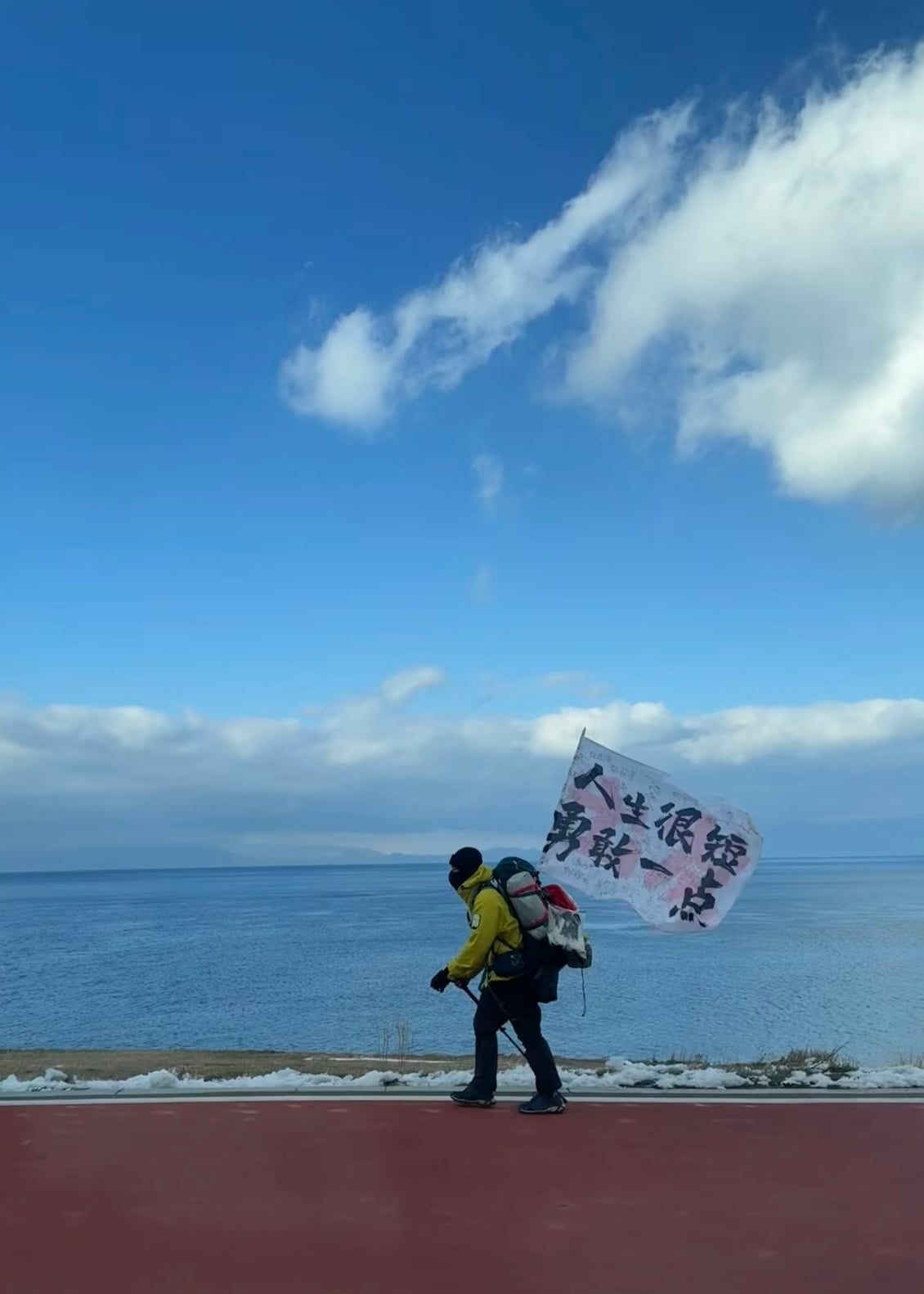 在青海湖边偶遇一位背包客，旗子上写着‘人生很短，勇敢一点’——瞬间被戳中了
