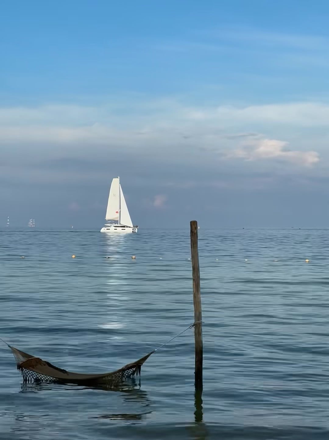 海风把 hammock 吹得像在跳舞 🌊 停泊的帆船是今天的背景板