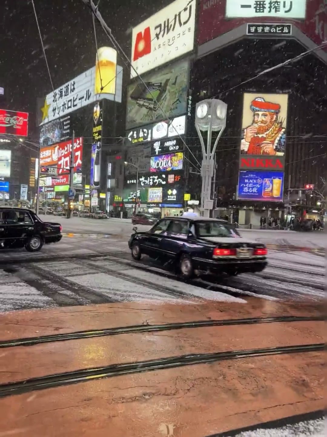 雪夜的札幌街角，黑色出租车裹着雪冲过斑马线