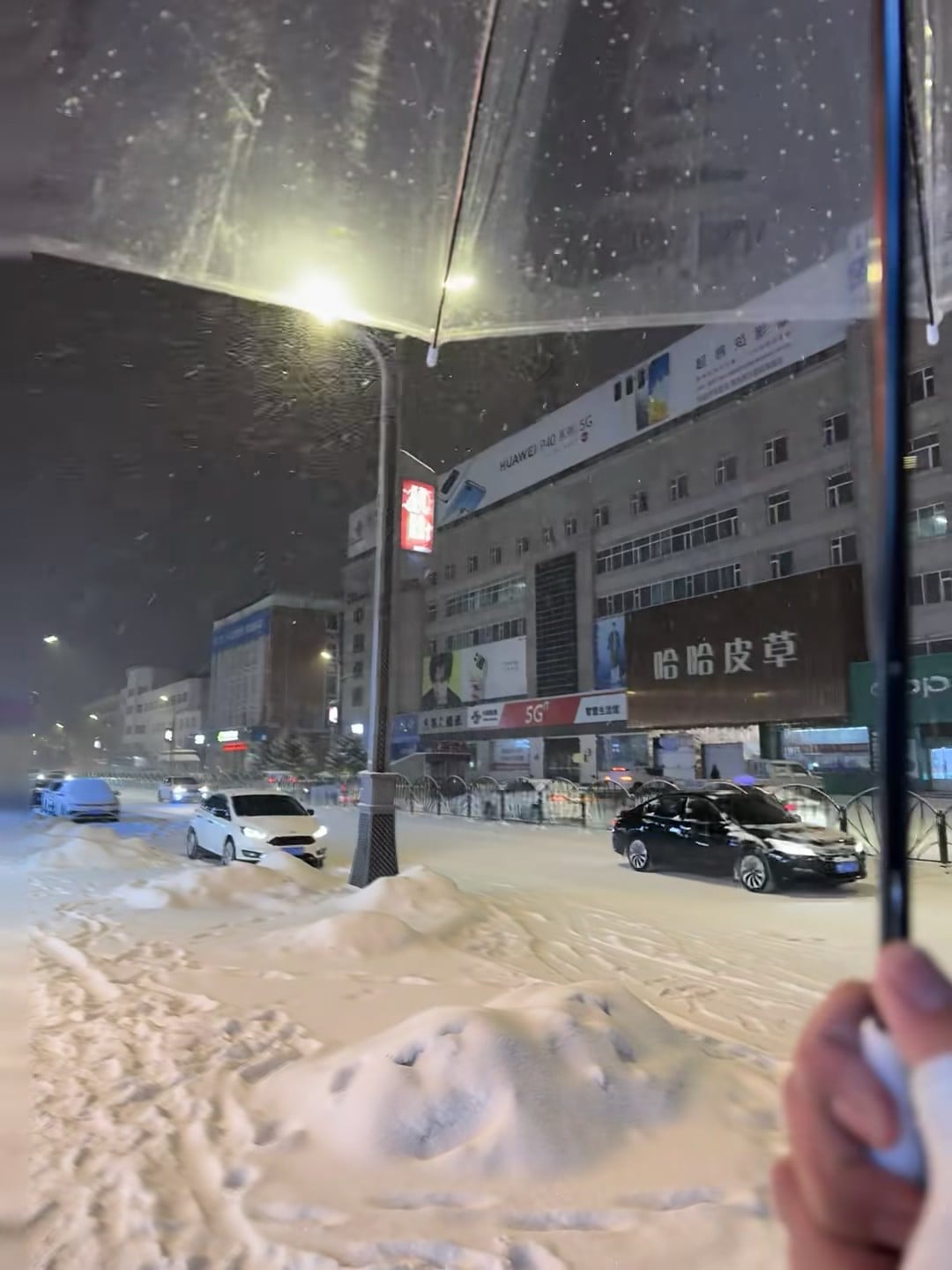 雪夜撑伞路过街角，车灯在雪里晕成一团暖光
